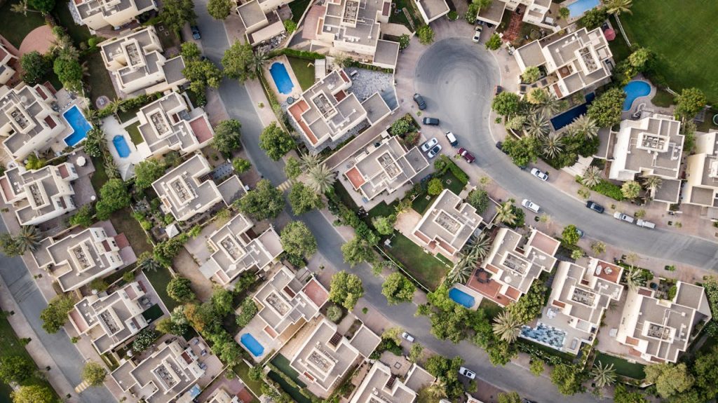 aerial-view-of-buildigns-1642125 Explore a stunning aerial view of a residential area in Dubai with lush greenery and swimming pools.